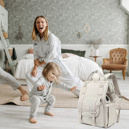sac à dos à langer biege et maman joue avec son bébé dans sa chambre