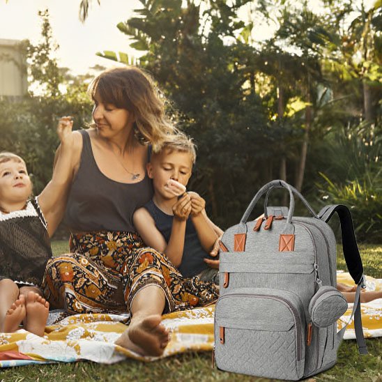 Sac à langer gris maman avec deux enfants au parc