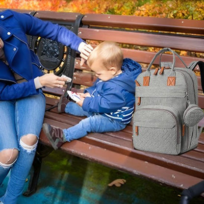 Sac à langer gris porté sur banc maman joue avec son bébé