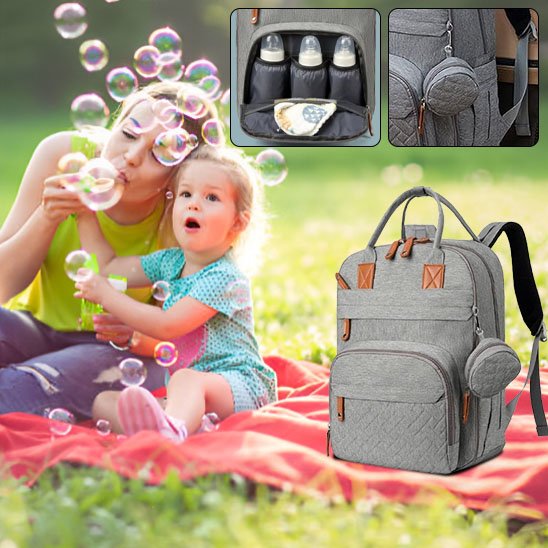 Sac à langer gris sur une nappe maman joue avec sa fille en piquenique