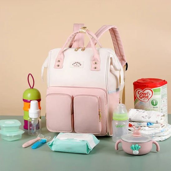 Sac a langer rose à plusieurs poches avec different produits bébé