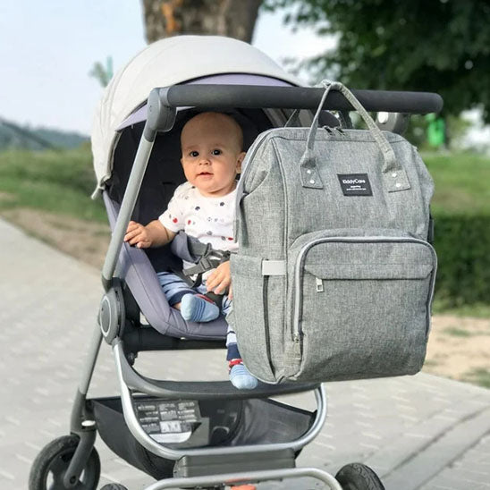 bebe en poussette sac a  langer gris accroche au guidon